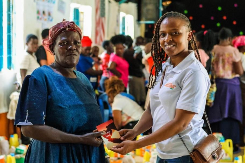 Faith Mutua, Accounts Officr, AEK Staff handing over the book of John to a new believer.